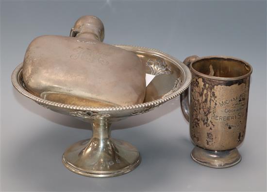 A George V silver spirit flask, a silver christening mug and a silver bon bon stand.